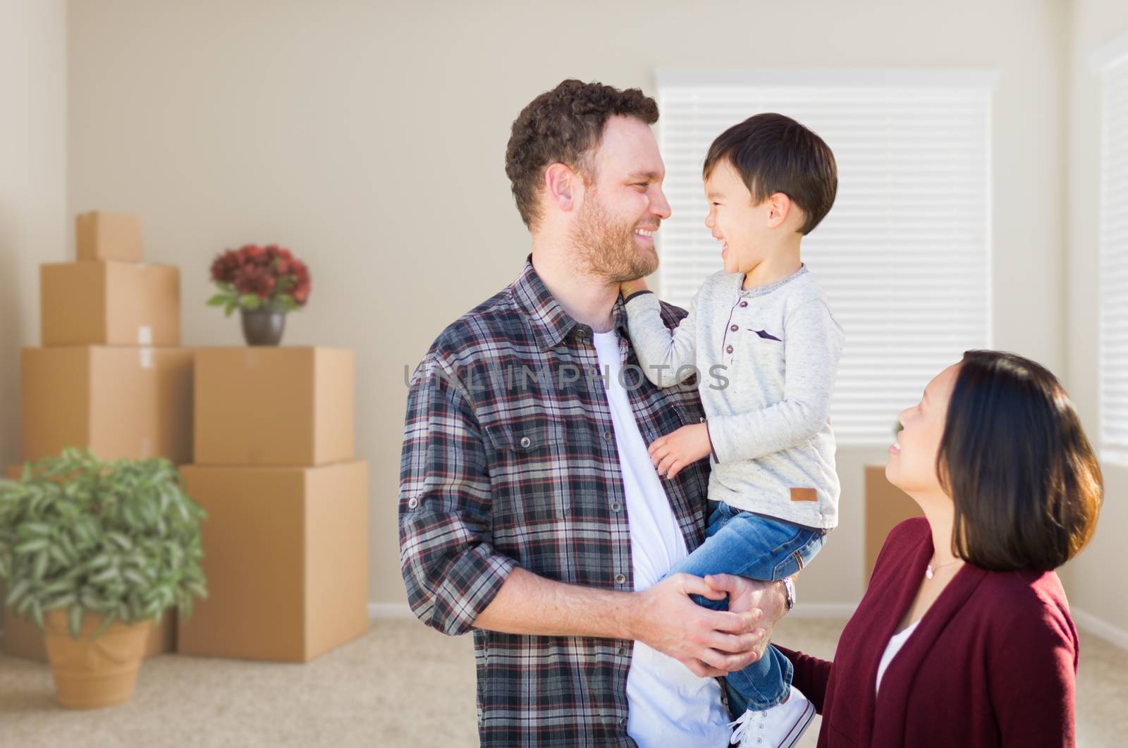Young Mixed Race Caucasian and Chinese Family Inside Empty Room with Moving Boxes. by Feverpitched