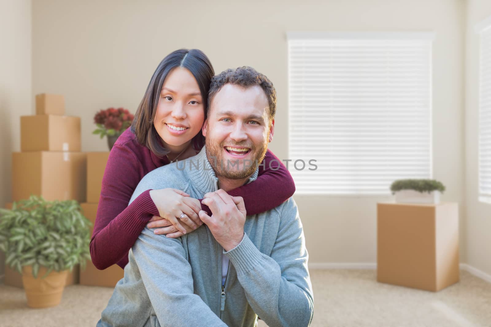 Mixed Race Caucasian and Chinese Couple Inside Empty Room with Moving Boxes.