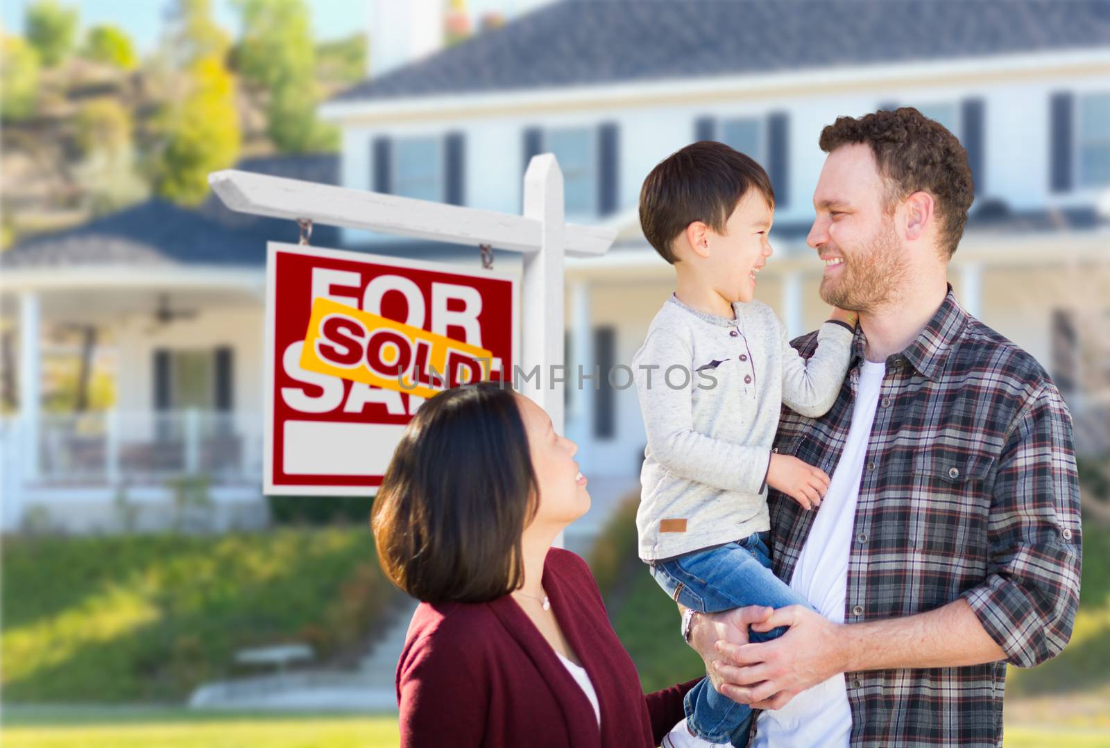 Young Mixed Race Caucasian and Chinese Family In Front of Sold For Sale Real Estate Sign and House. by Feverpitched
