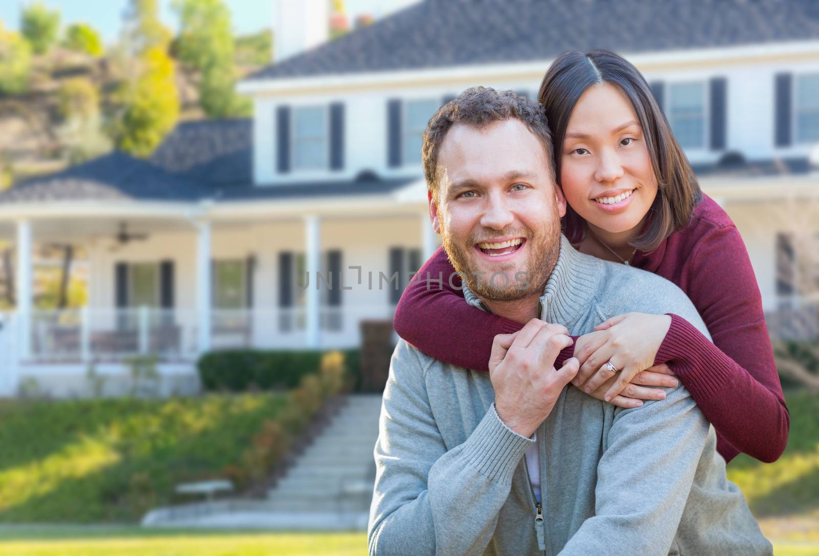 Mixed Race Caucasian and Chinese Couple In Front Yard of Beautiful Custom House.