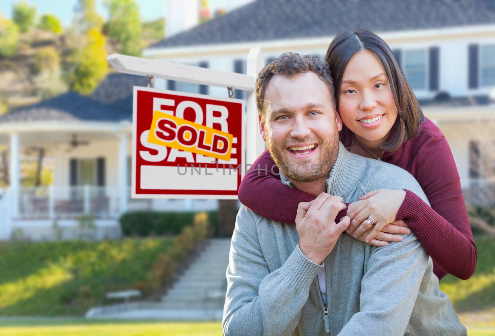 Mixed Race Caucasian and Chinese Couple In Front of Sold For Sale Real Estate Sign and House. by Feverpitched