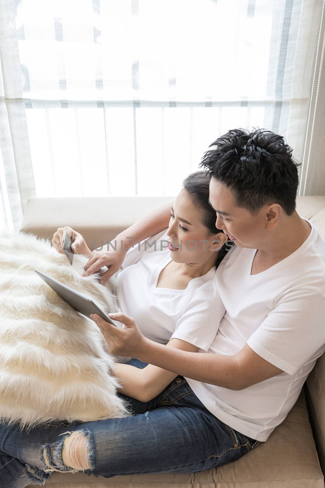 Young Couples using tablet to shopping with credit card in living room of contemporary house for modern lifestyle and e-commerce concept