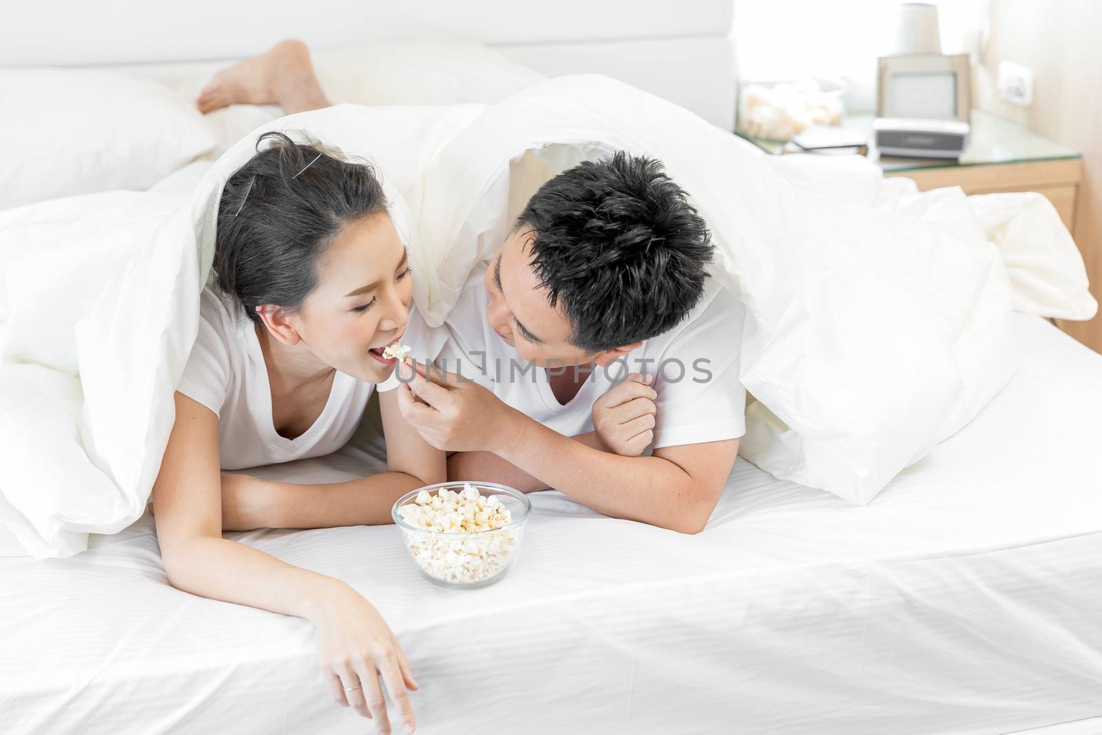 Young Asian Couples having breakfast on bed together in bedroom of contemporary house for modern lifestyle concept