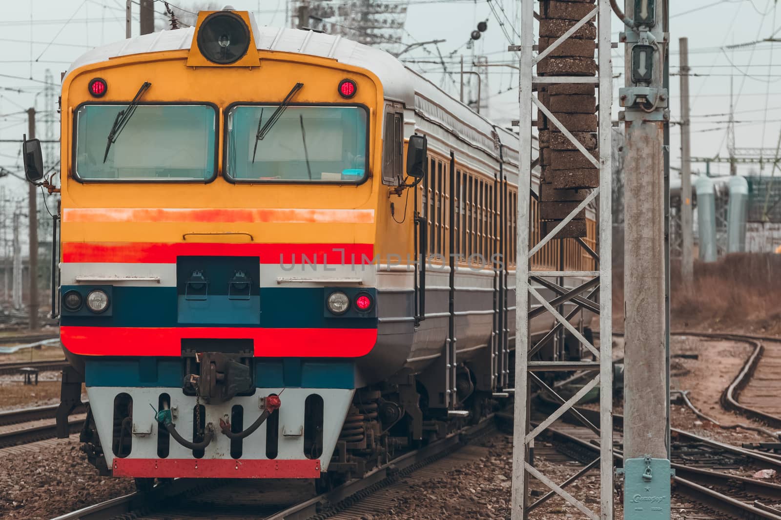 Old yellow passenger diesel train moving at the terminal