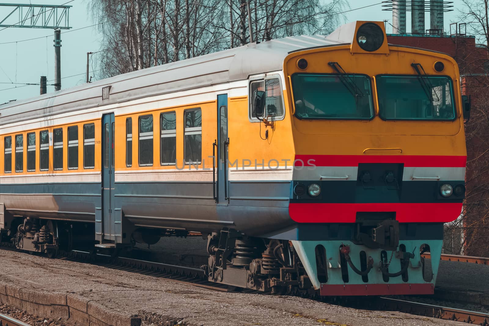 Old yellow passenger diesel train moving at the terminal