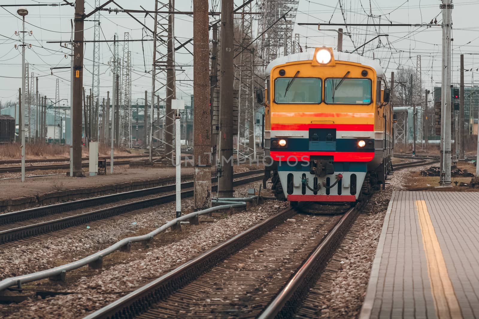 Old yellow passenger diesel train moving at the terminal