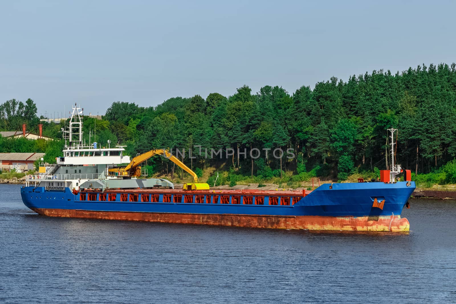 Blue cargo ship with long reach excavator moving to the port