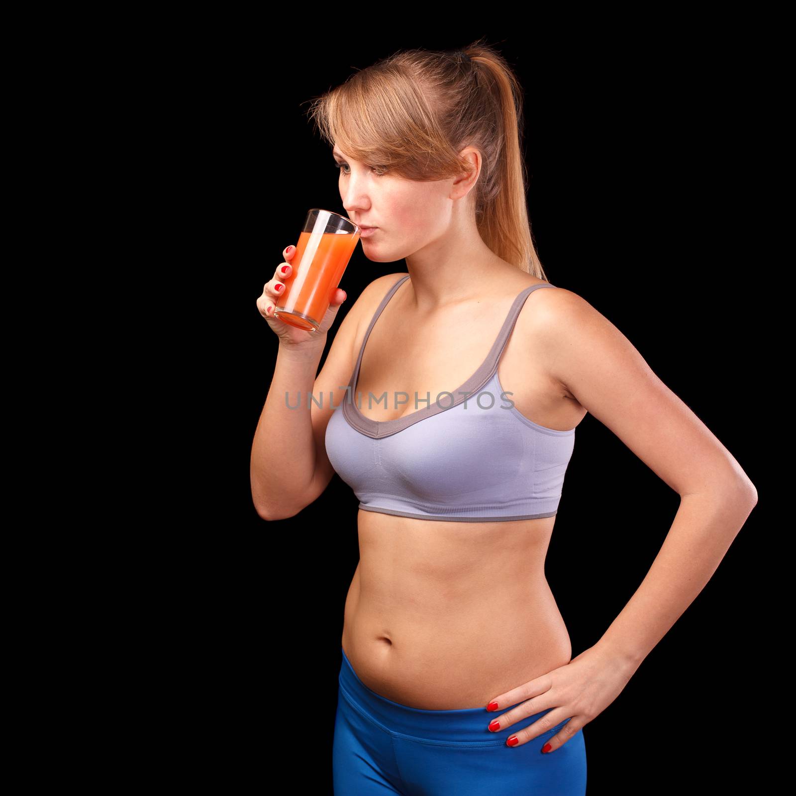 The girl who was engaged in sports, is on a black background with a glass of grapefruit juice.