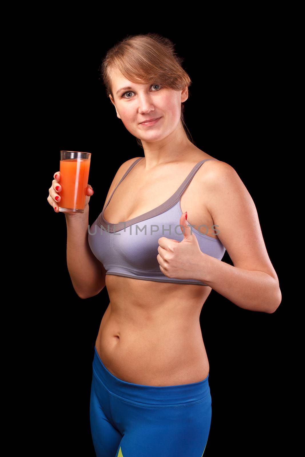 The girl who was engaged in sports, is on a black background with a glass of grapefruit juice.