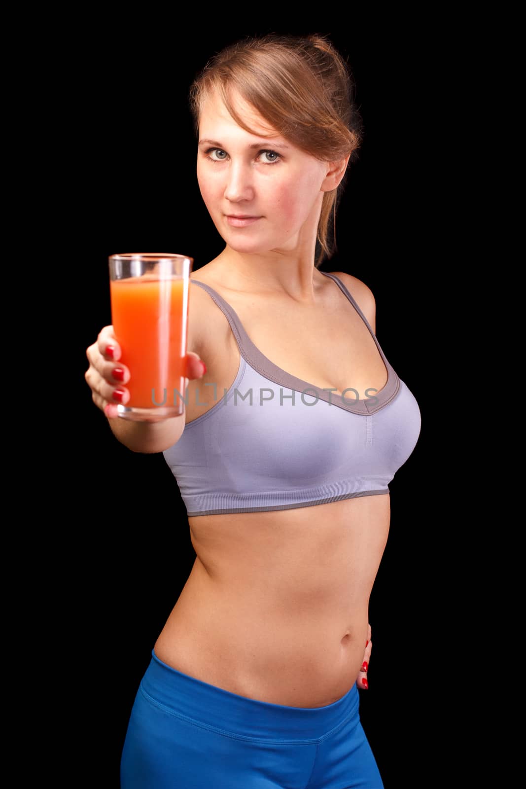 The girl who was engaged in sports, is on a black background with a glass of grapefruit juice.