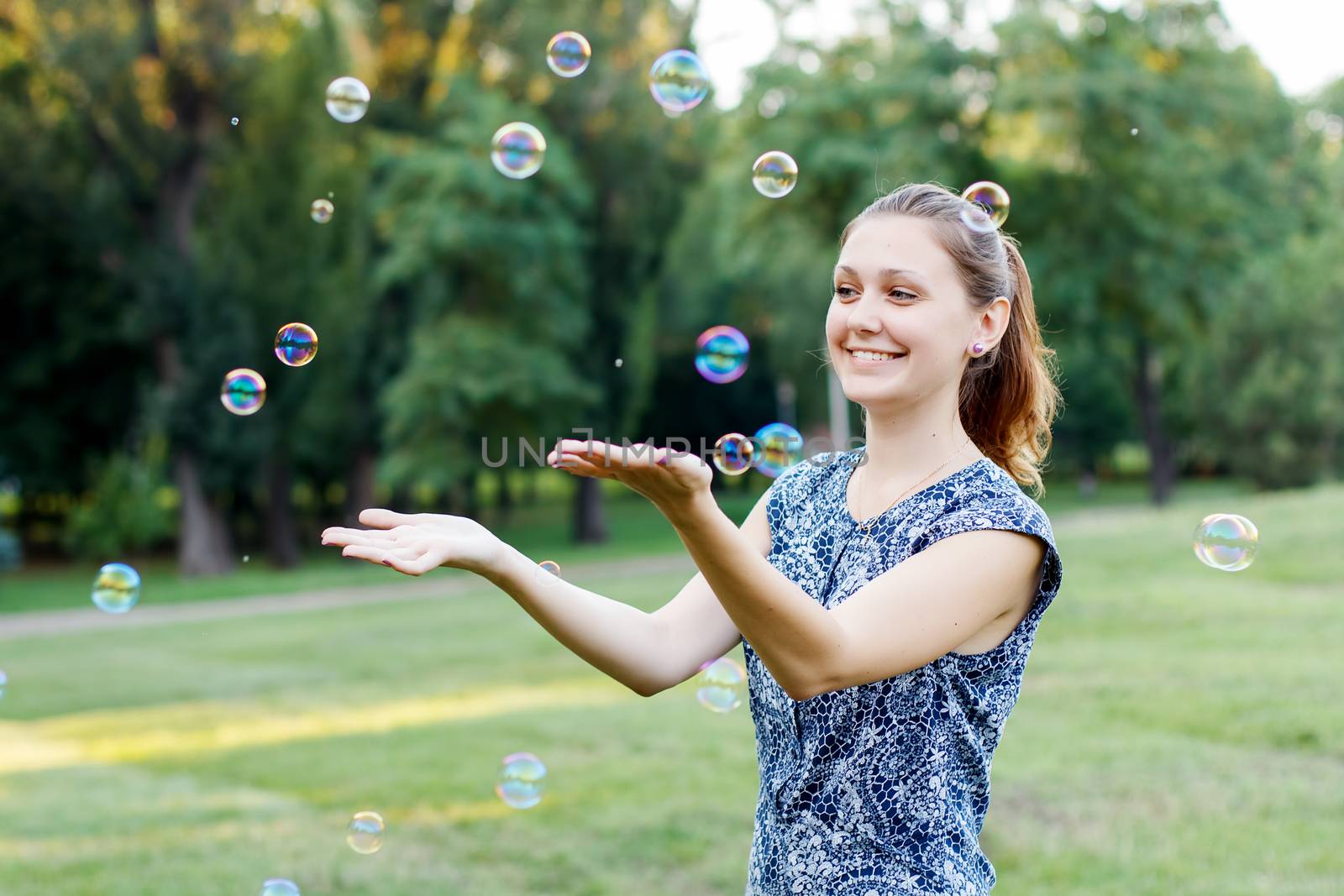Beautiful girl in the park with soap bubbles.