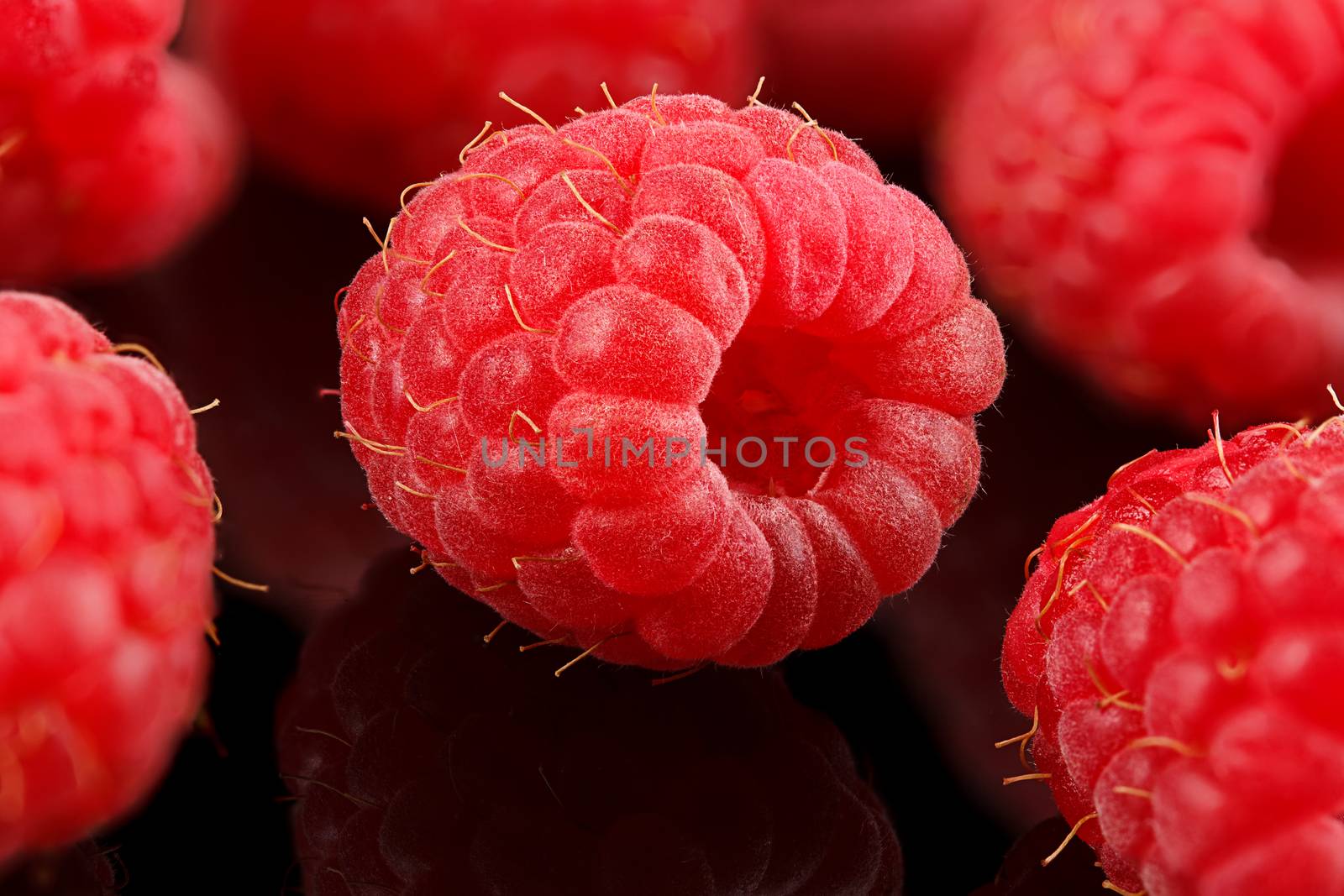 A bunch of ripe raspberries on black background.