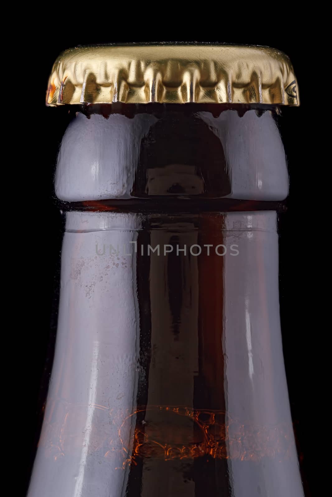 Closed, brown beer bottle on a black background.