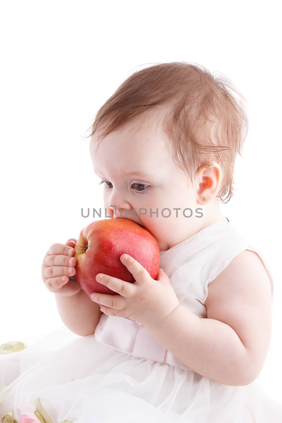 The girl is one year in dress sitting on a white background.