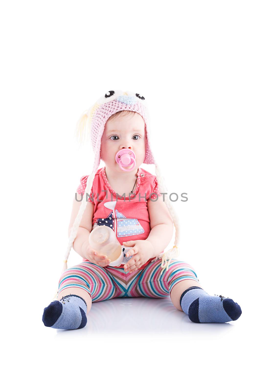 The girl is one year in dress sitting on a white background.