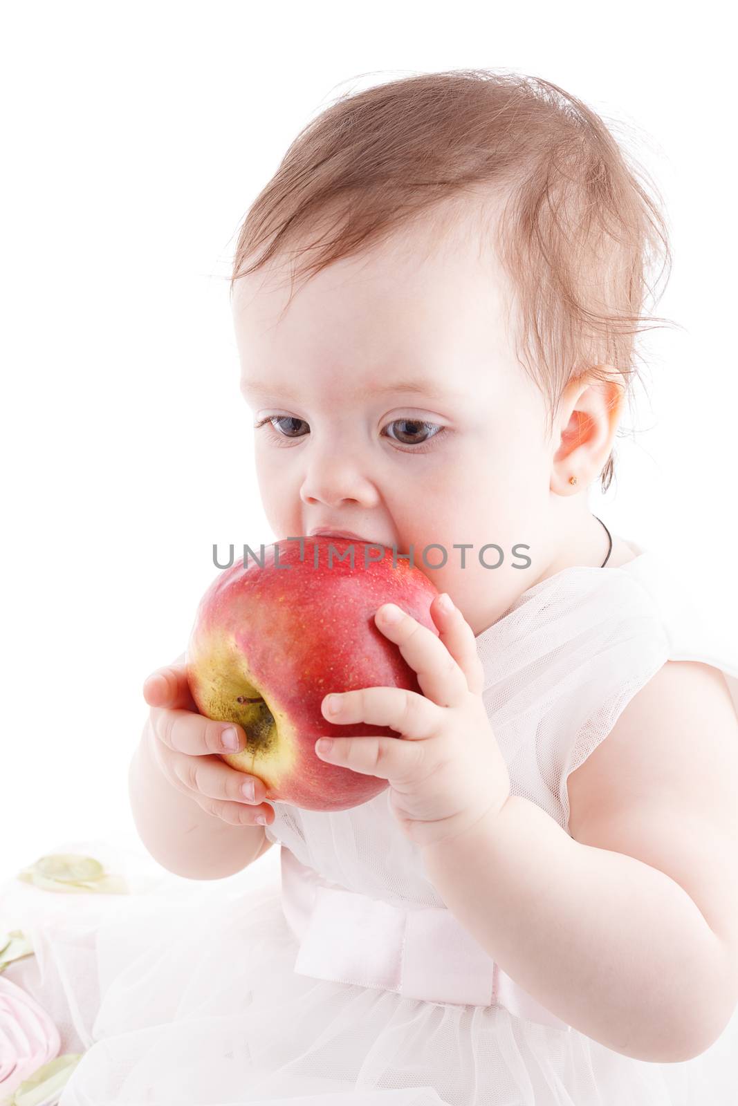 The girl is one year in dress sitting on a white background.