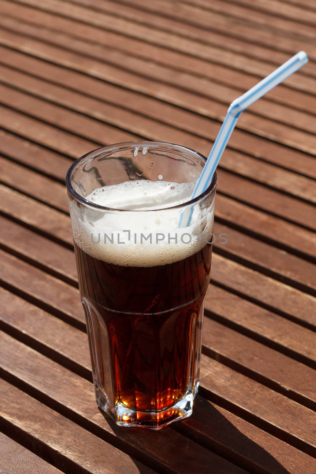 Cocktail with straw on the wooden table.