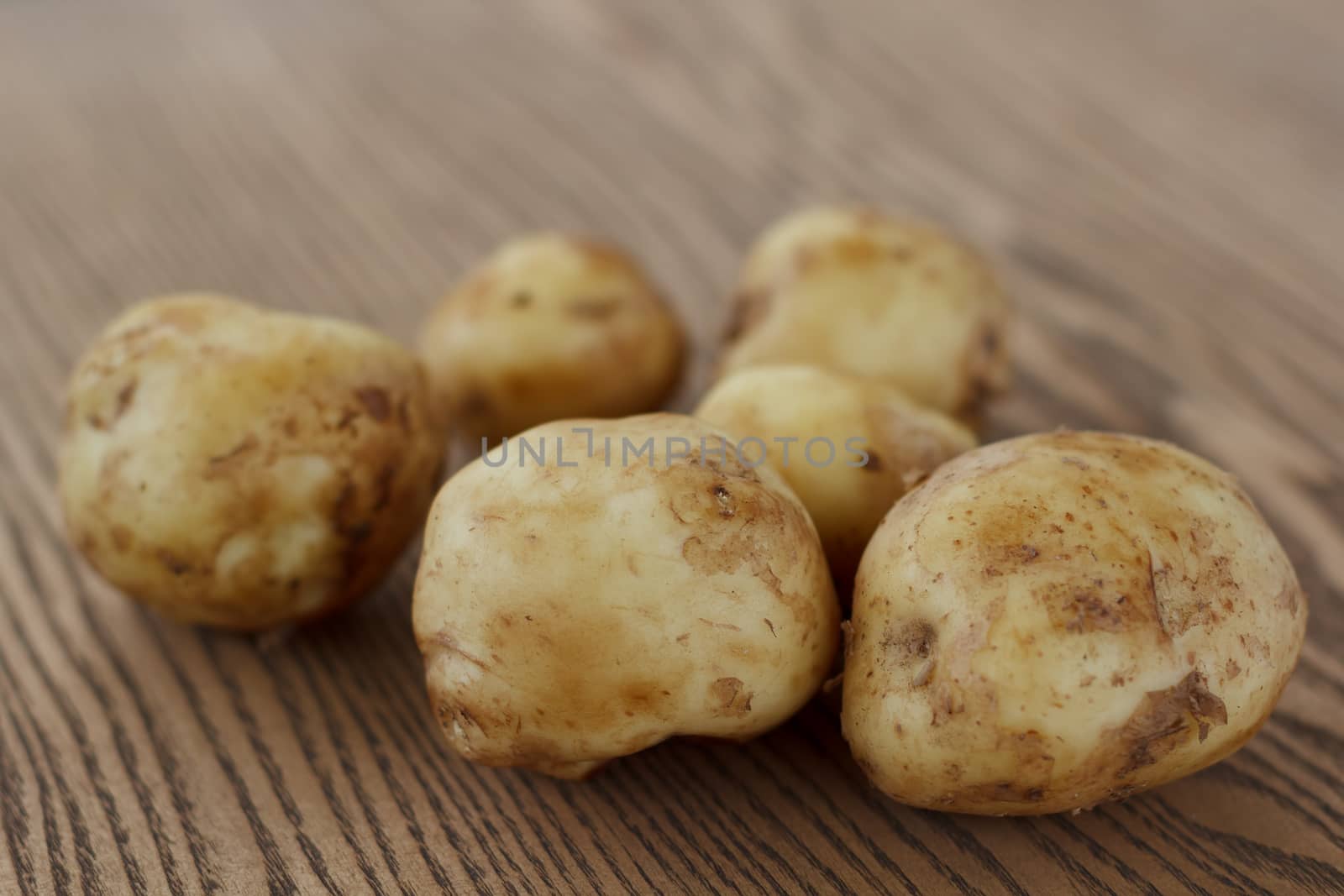 Heap of raw potato lying on the wooden background.