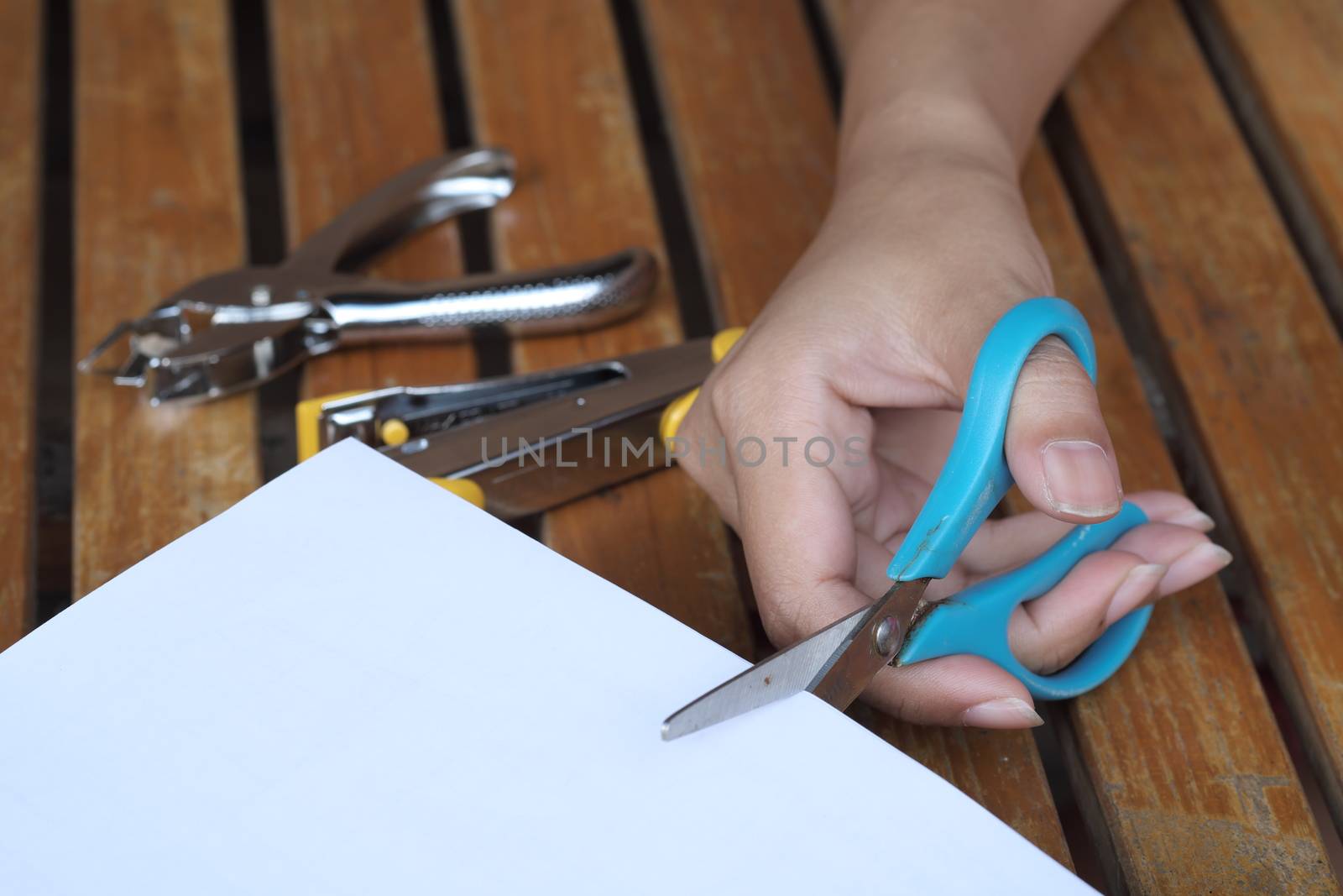 Hand holding black correction tape roller on table.