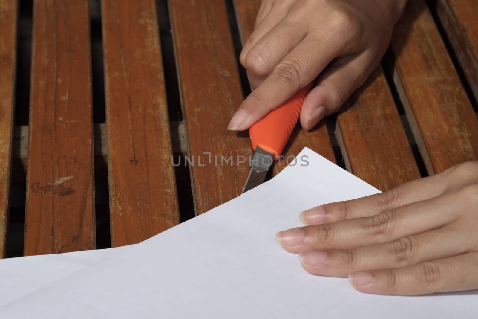 women hands cutting carton with a knife on a paper. Close up handwork.