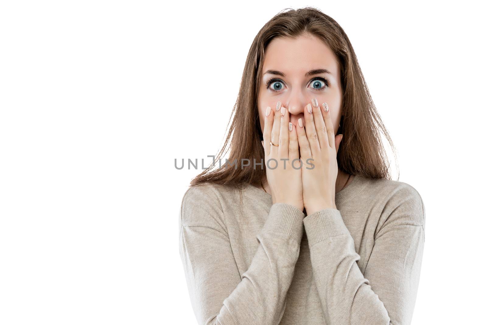 surprised young girl covers her mouth with her hands on a white background isolated