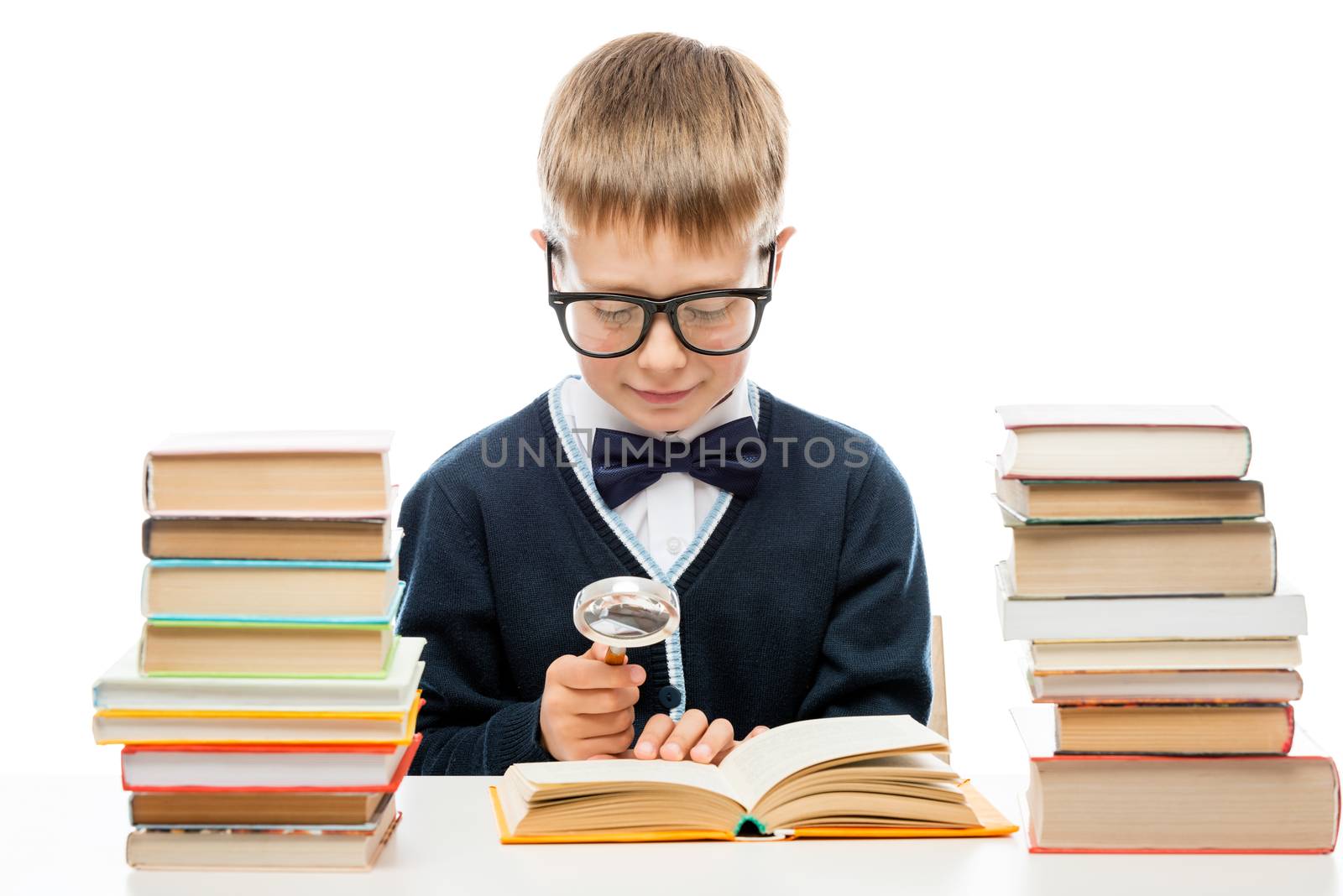 smart boy with glasses with a magnifying glass is considering the text of the book, portrait isolated