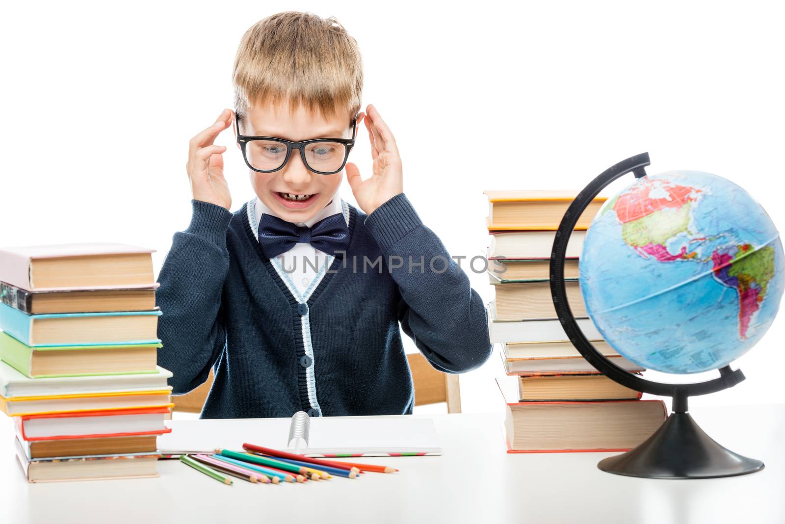 angry schoolboy with books at the table on a white background