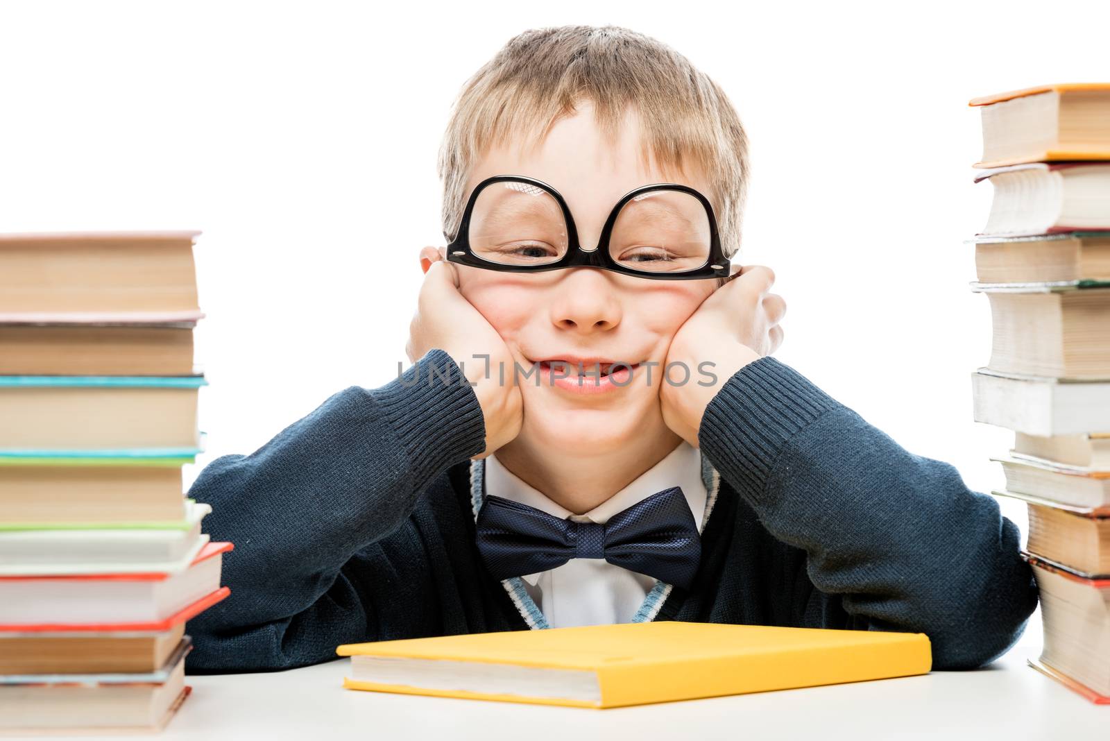 funny schoolboy and piles of books on white background, close-up portrait