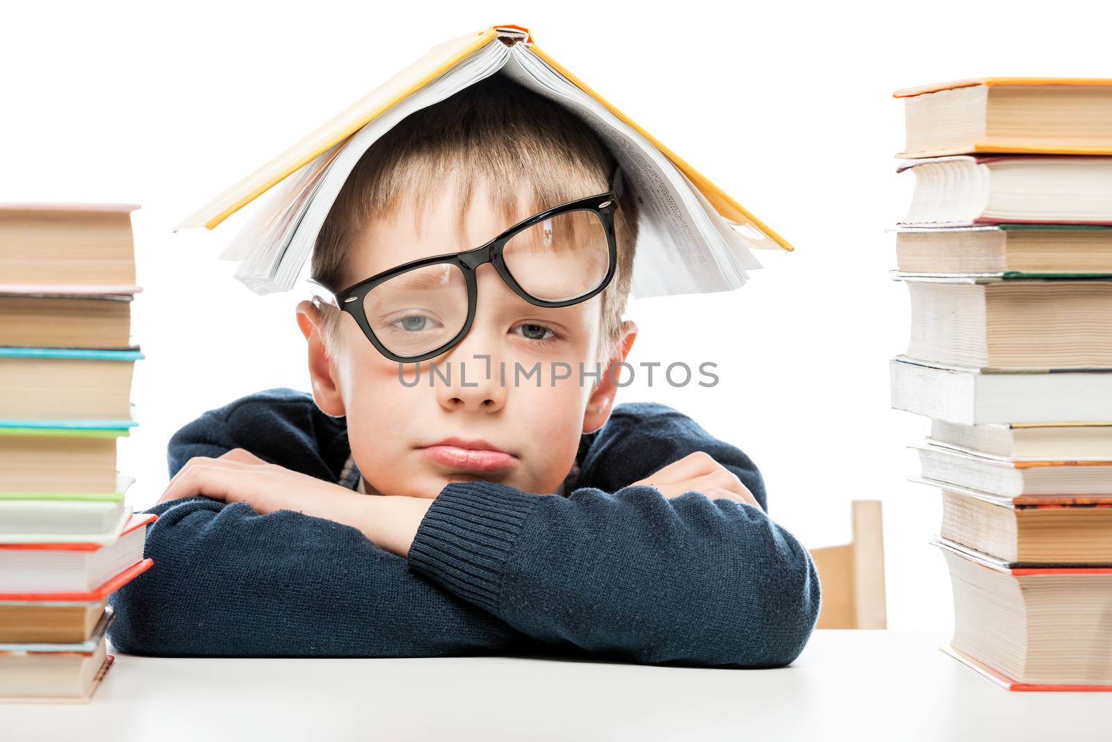 tired schoolboy and piles of books on white background, close-up portrait