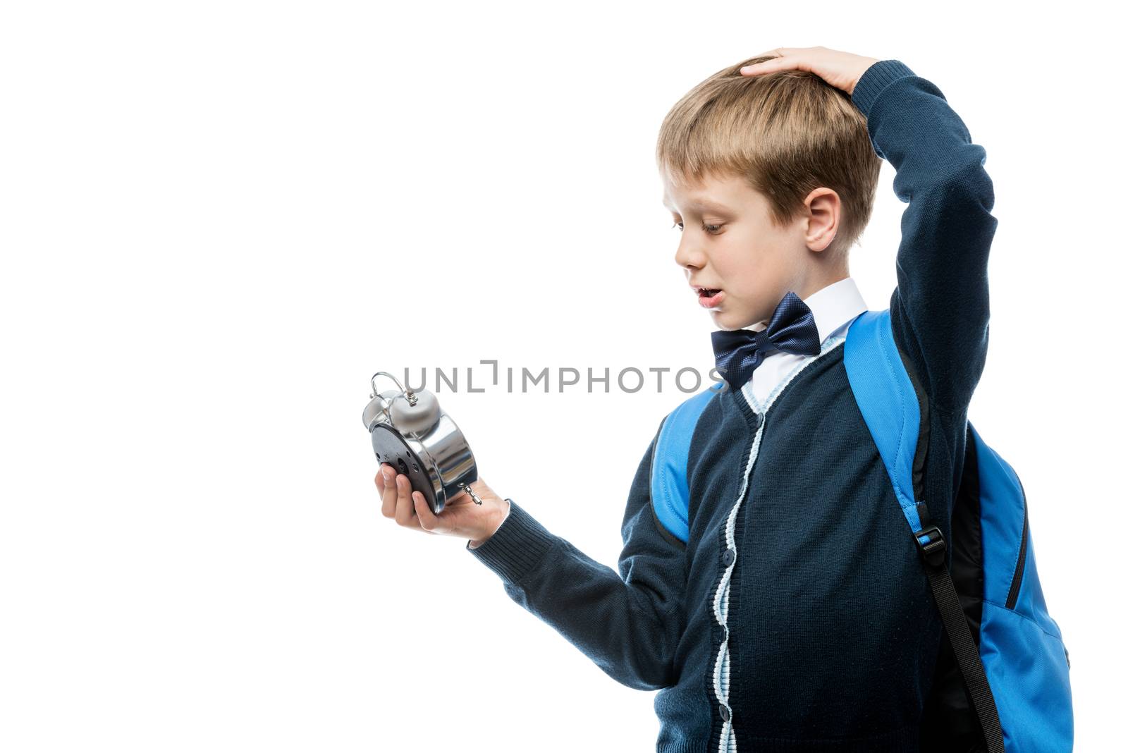 portrait of a boy in school uniform with an alarm clock on white background