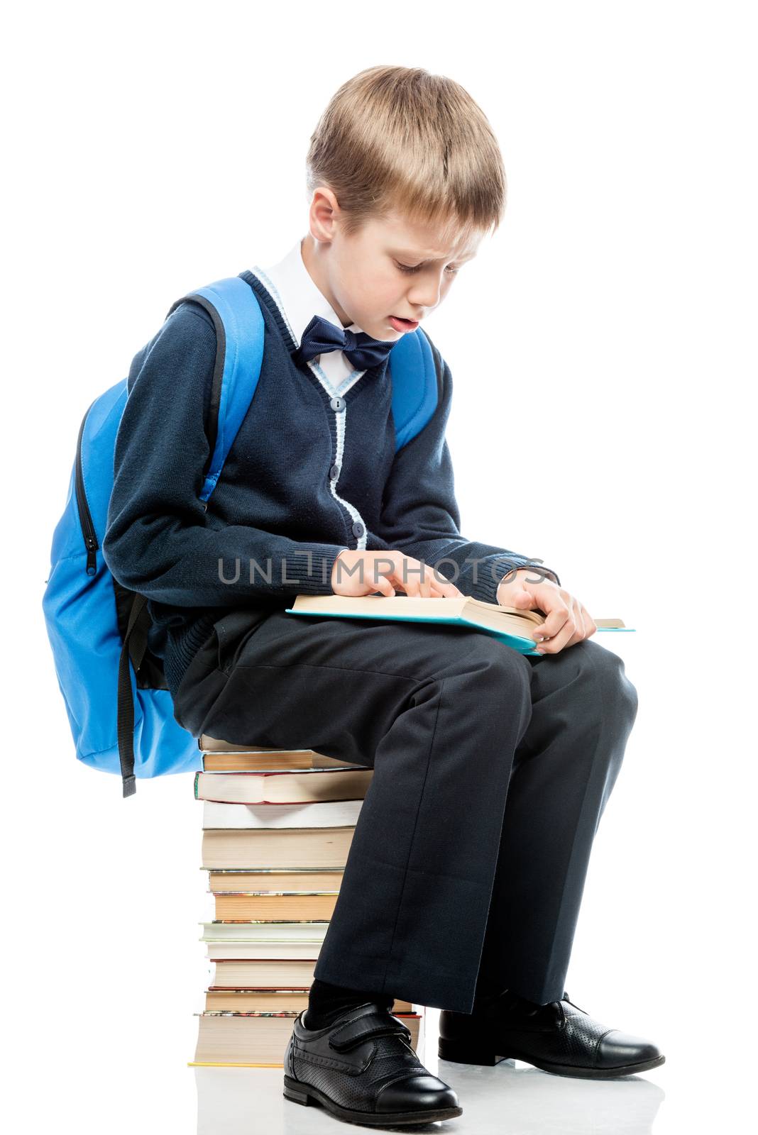 the student is sitting on a pile of books and reads a textbook on a white background