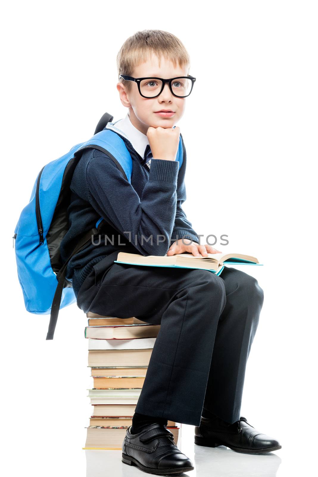 boy in school uniform with books on a white background in studio