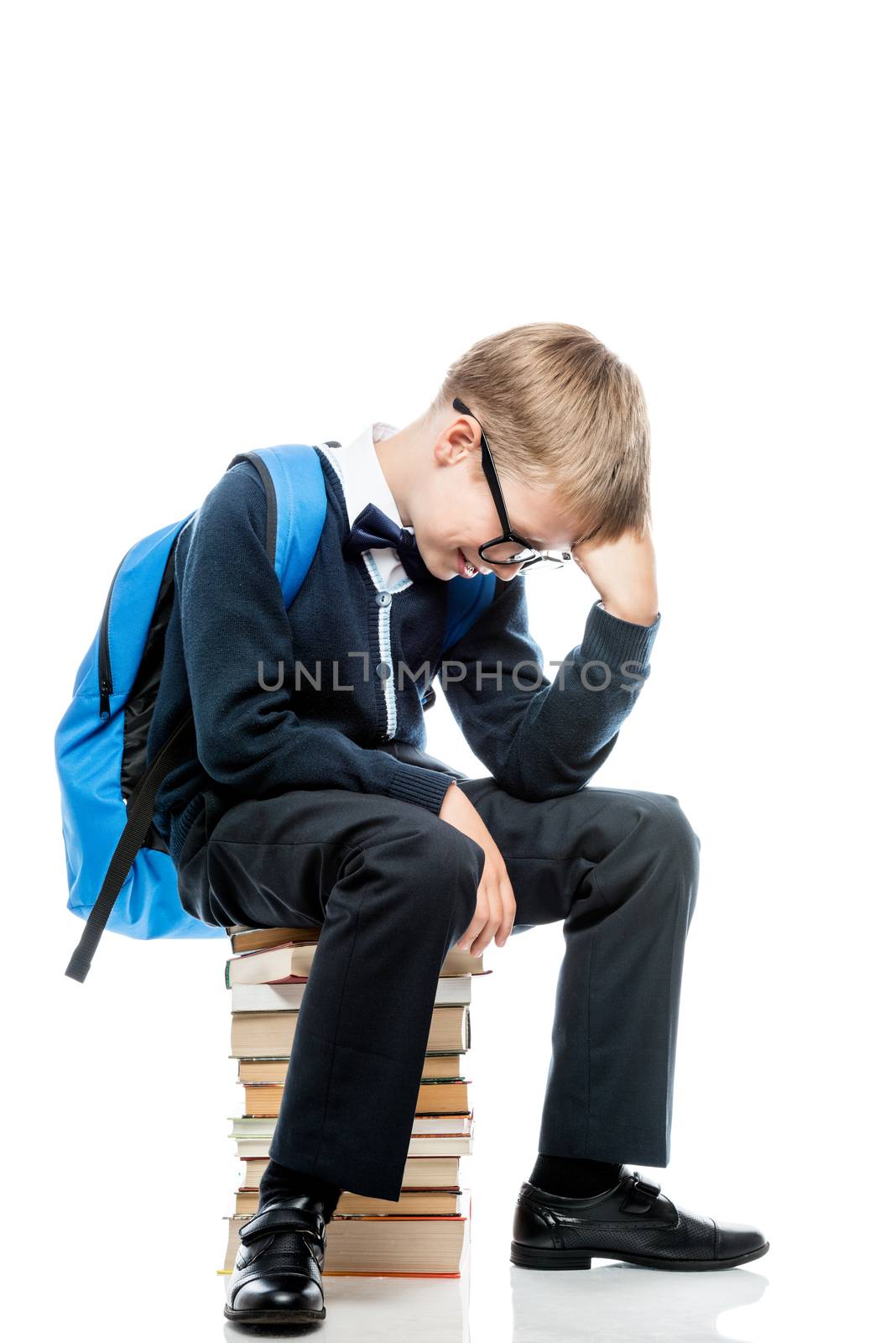 a boy in thought sits on a pile of books on a white background