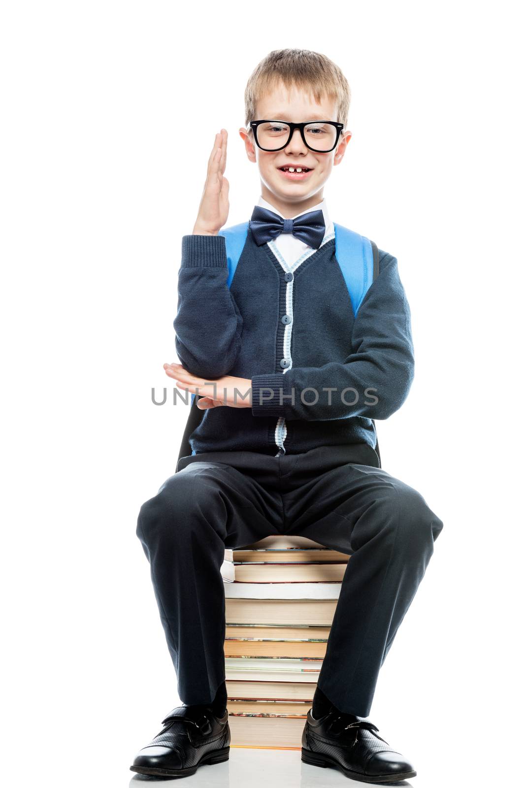 smart schoolboy ready to meet a lesson, a schoolboy sits on a pile of books on a white background