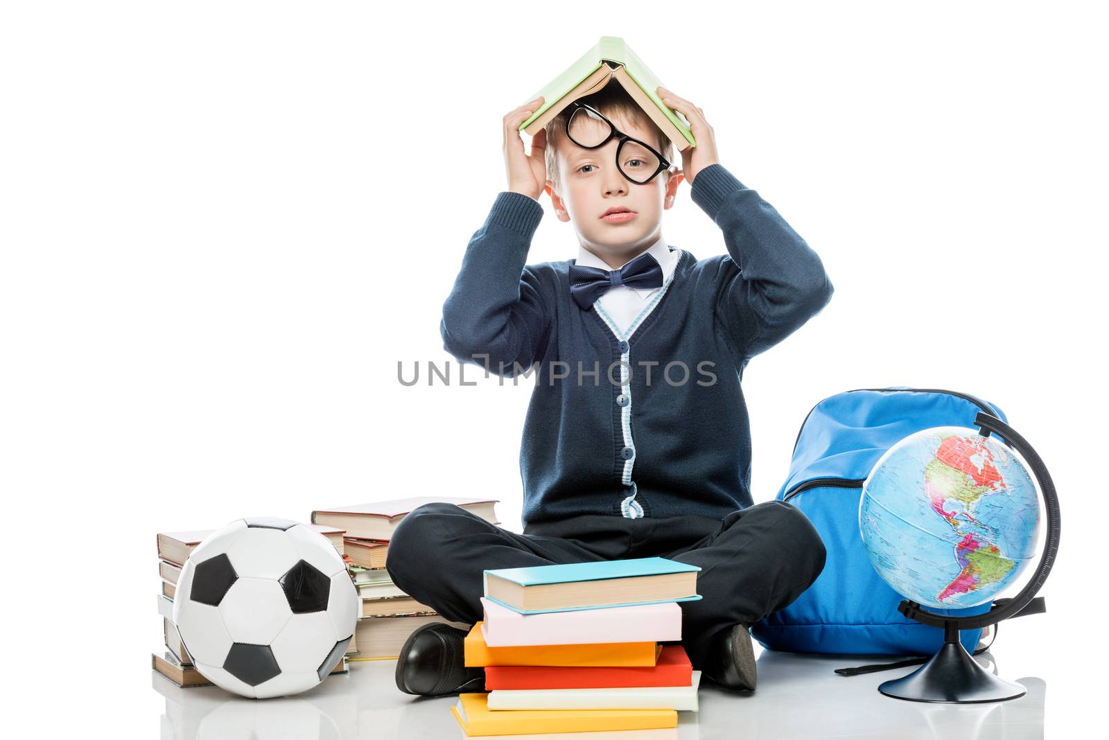 tired schoolboy with book on his head posing against white backg by kosmsos111