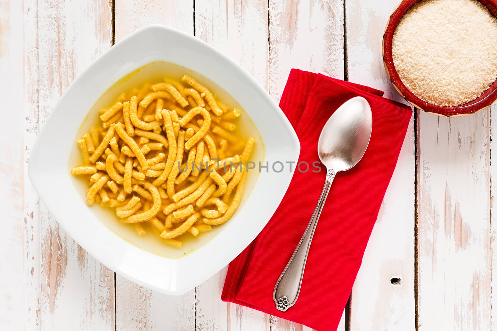 Italian passatelli in broth over a rustic table seen from above