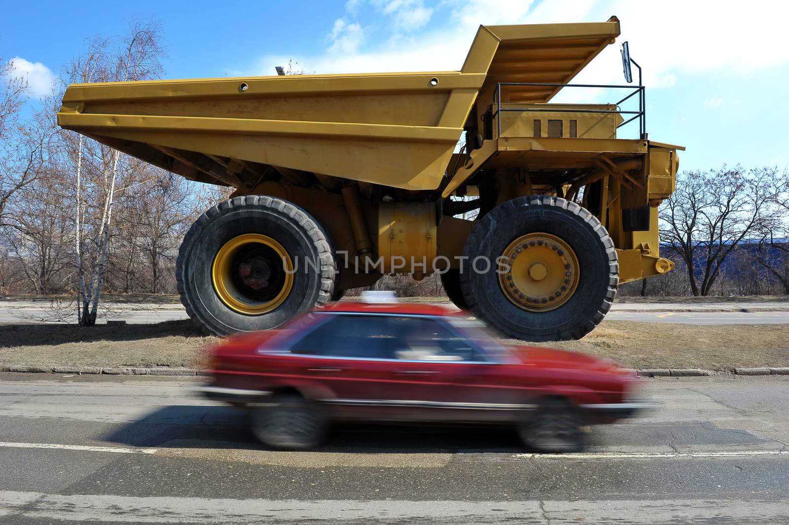 Small cars passing by big yellow mining truck