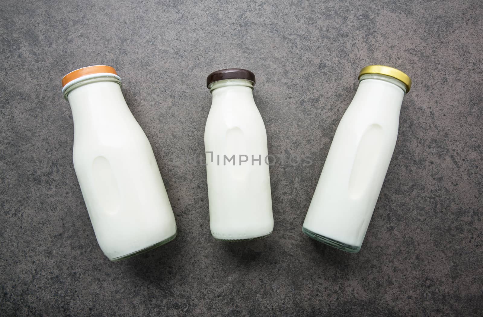 Milk bottle on dark stone background. Top view with copy space.