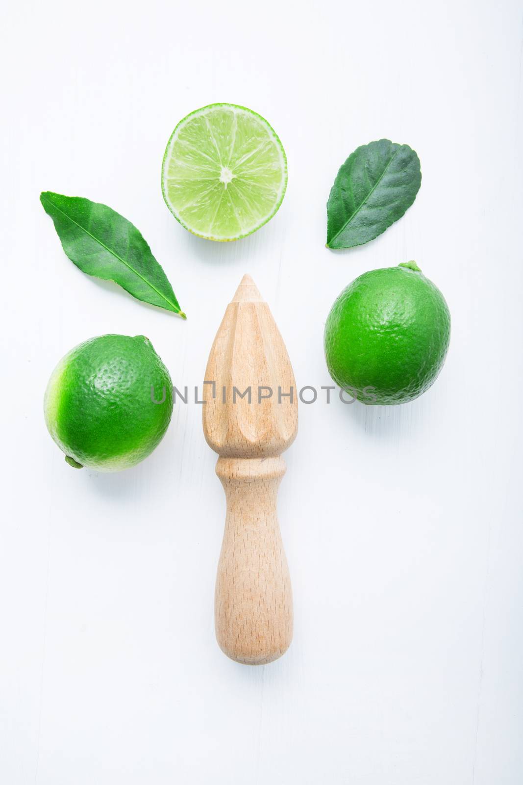 Fresh limes and wooden juicer on white background. Top view with by Bowonpat