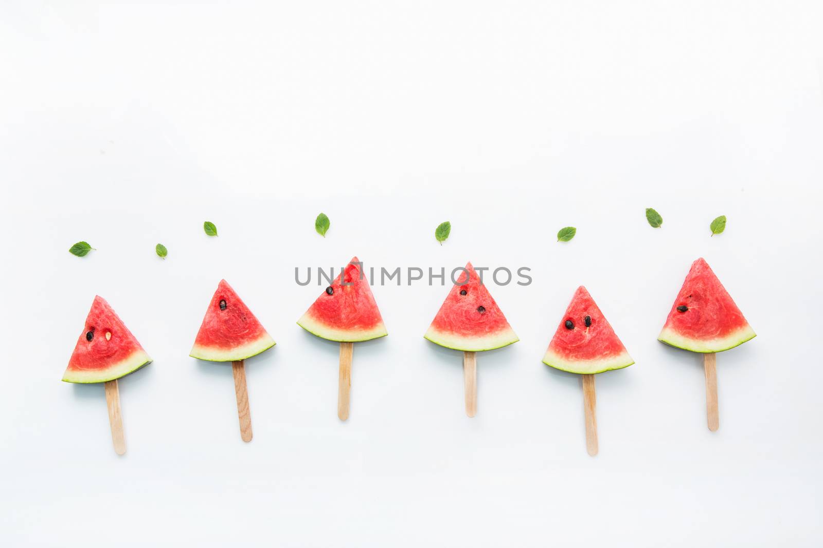 Watermelon slice popsicles and paper mint on white wooden backgr by Bowonpat