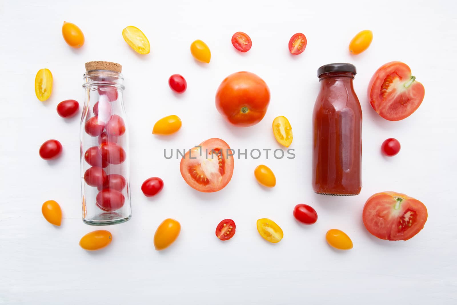 Tomatoes juice in bottle and fresh tomatoes on white wooden background.