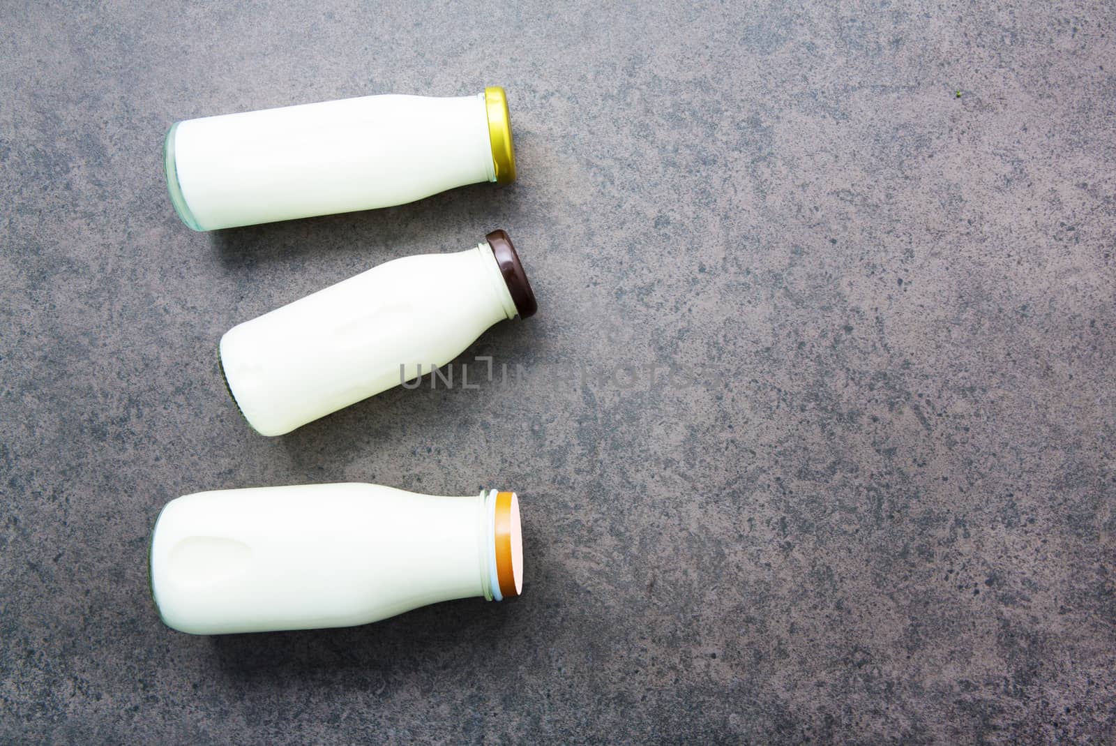 Milk bottle on dark stone background. Top view with copy space.