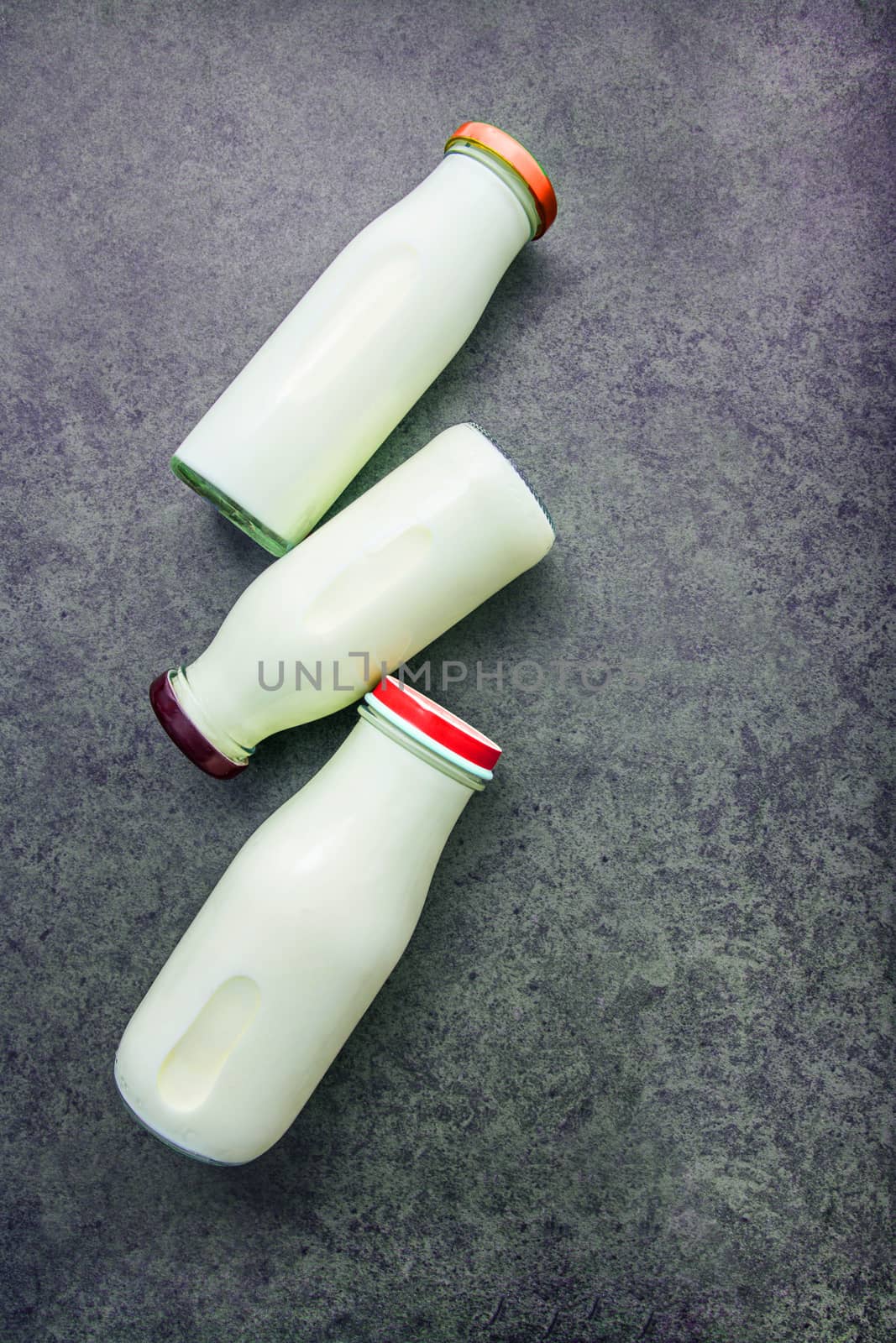 Milk bottle on dark stone background. Top view with copy space. by Bowonpat