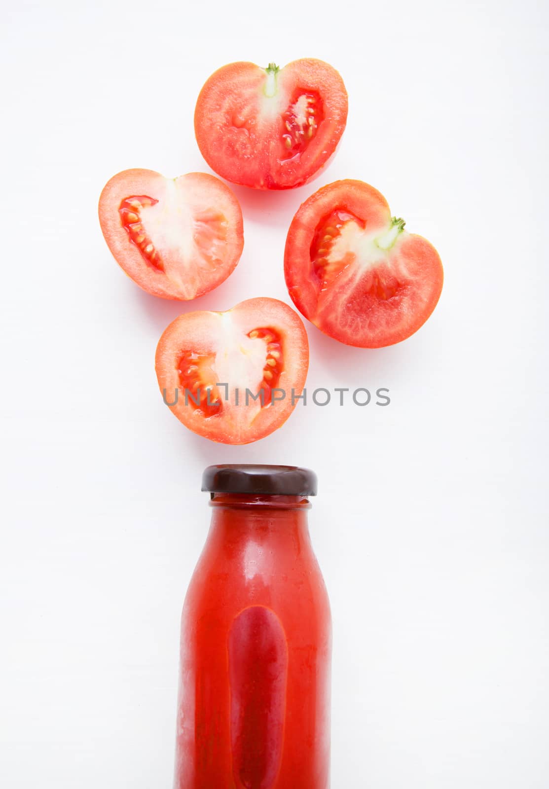 Tomatoes juice in bottle and fresh tomatoes slices on white wood by Bowonpat