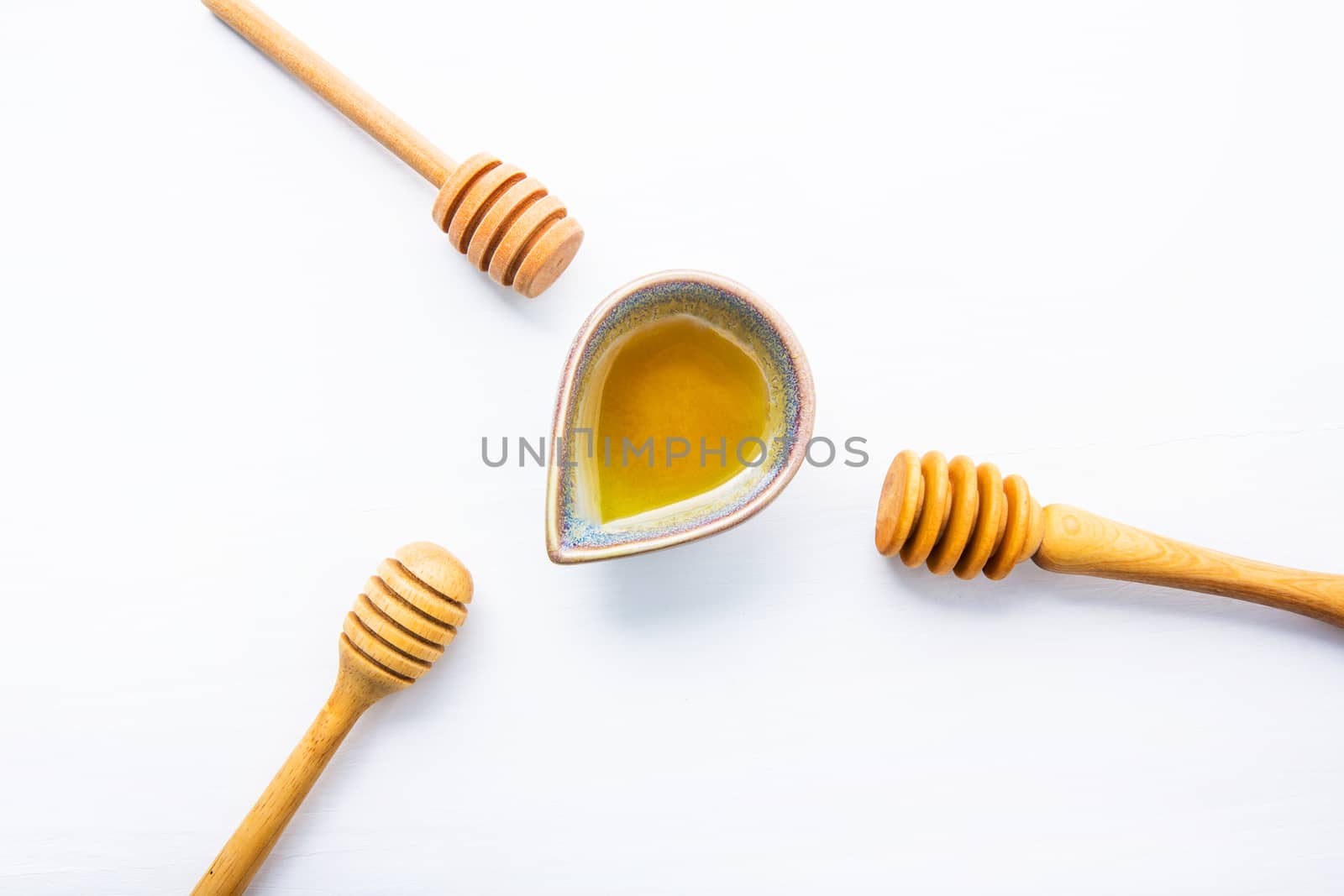 Honey with wooden dipper on white wooden background.