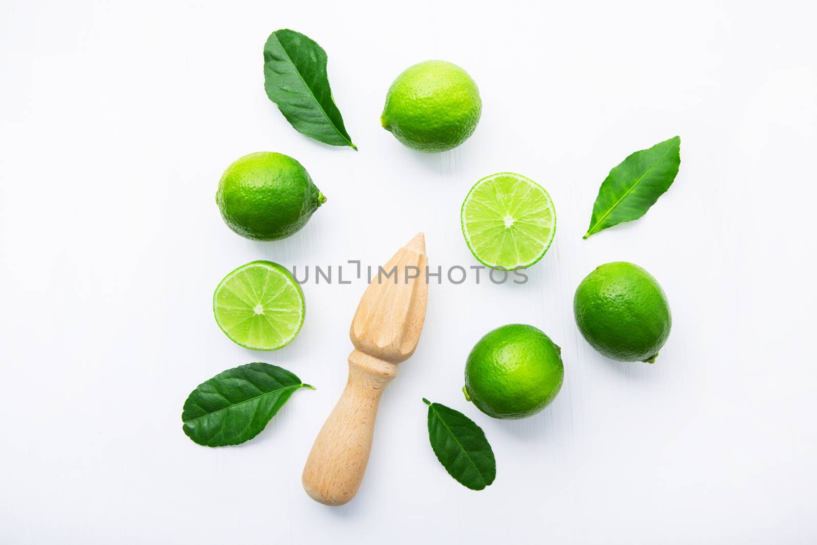 Fresh limes and wooden juicer on white background. Top view with by Bowonpat