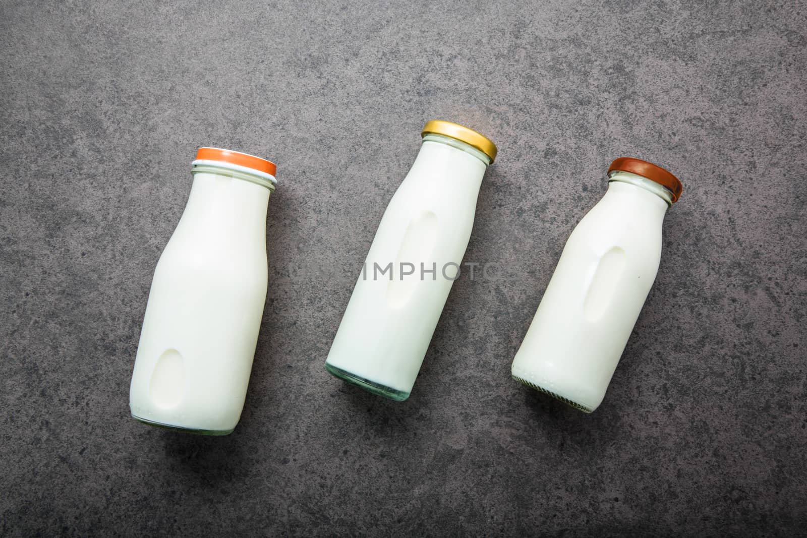 Milk bottle on dark stone background. Top view with copy space. by Bowonpat