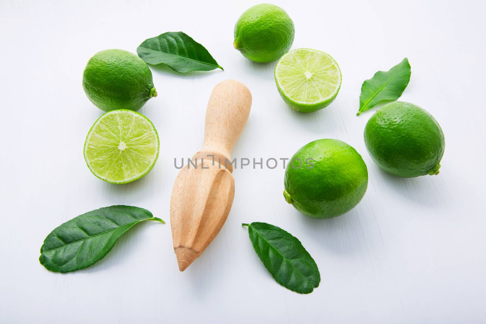 Fresh limes and wooden juicer on white background. Top view with by Bowonpat