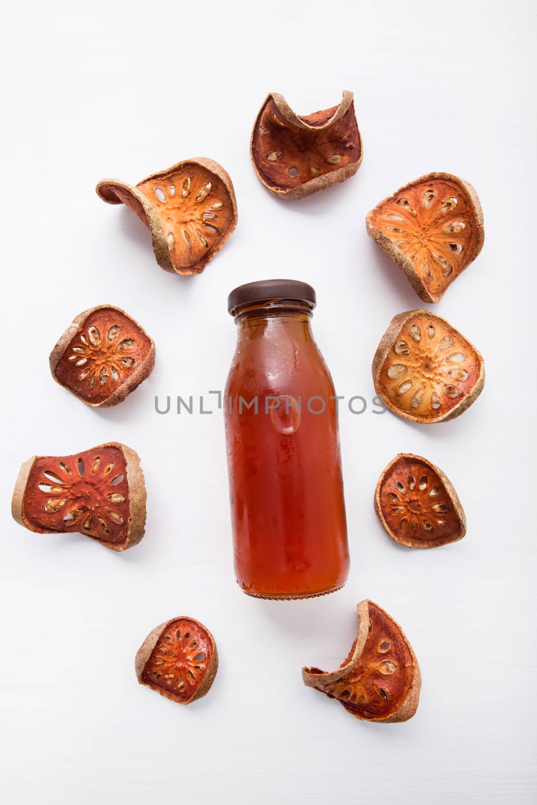 Bael dried and bael juices on white wooden background.