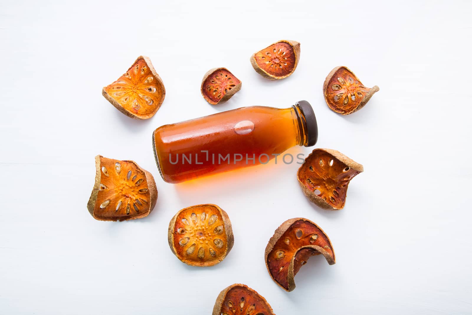 Bael dried and bael juices on white wooden background. by Bowonpat